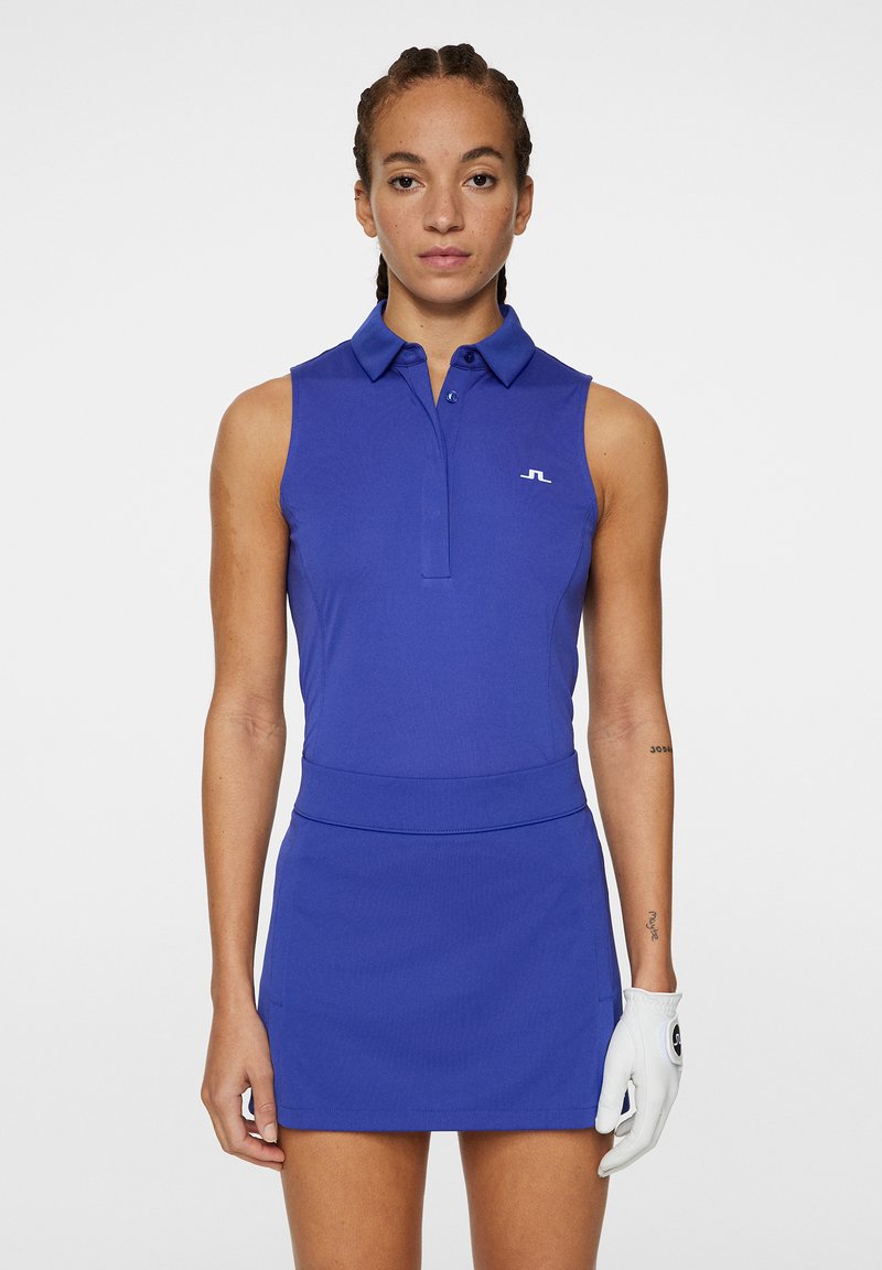 Ärmlös blå polo-klänning med krage, figurnära midja och slät yta. Har en liten vit logotyp på bröstet och en vit handske.