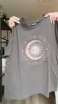 Szary bawełnowy t-shirt z okrągłym graficznym wzorem słońca i księżyca, z niebieskim słońcem i tekstem w jasnych kolorach. Krótkie rękawy i okrągły dekolt.