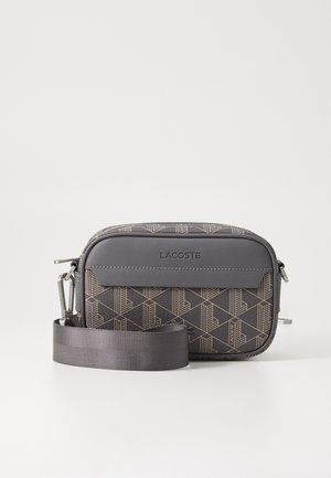 Lille rektangulær Lacoste crossbody taske med gråt geometrisk mønster, gråt frontpanel og justerbar grå rem på hvid baggrund.