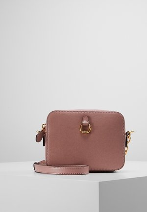 Obdélníková mauve kožená kabelka přes rameno se zlatým kováním, zapínáním na zip a nastavitelným páskem, na bílém povrchu na světle šedém pozadí.