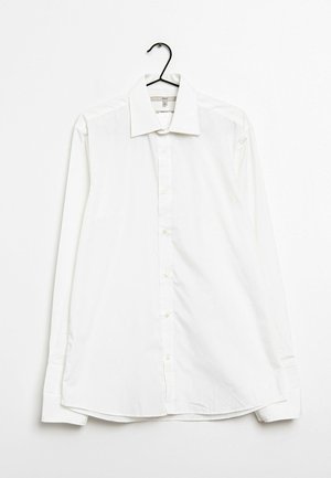 Biała, długorzędowa koszula z guzikami na wieszaku. Posiada klasyczny kołnierzyk, guziki z przodu i lekko zaokrąglony dół. Gładka, jednolita tekstura.