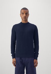 Mørkeblå striktrøje med rund halsudskæring og ribbede manchetter og kant. Stoffet ser tekstureret ud og har en medium vægt.