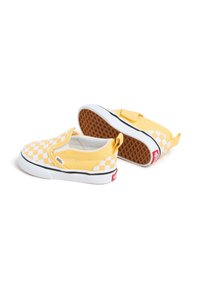 Bottines jaunes en toile à enfiler avec un motif en damier blanc, semelle en caoutchouc et une rayure noire. Comprend une sangle Velcro et un détail de logo.