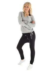 Gray long-sleeve top with dropped shoulders paired with fitted black sweatpants featuring a side zipper and drawstring waist, worn with white sneakers.