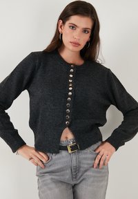 Dark gray knit cardigan with long sleeves, round neckline, and a row of metallic buttons down the front. Slightly cropped with ribbed hem.