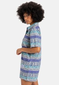 Short-sleeve shirt dress in blue and purple with geometric patterns, featuring a collar, button front, and side pocket detail.