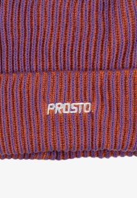 Dzianinowa czapka typu beanie w naprzemiennych pomarańczowych i fioletowych paskach, z pionowym prążkowaniem i białym logo „PROSTO” wyszytym z przodu.