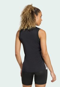 Top atlético negro sin mangas con una textura suave, que presenta un diseño ajustado y paneles laterales en gris contrastante, combinado con pantalones cortos negros.