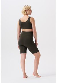 Oliven grøn ribbet sportsbh og højtaljede shorts, der har et tætsiddende design, blød tekstur og minimale syninger.