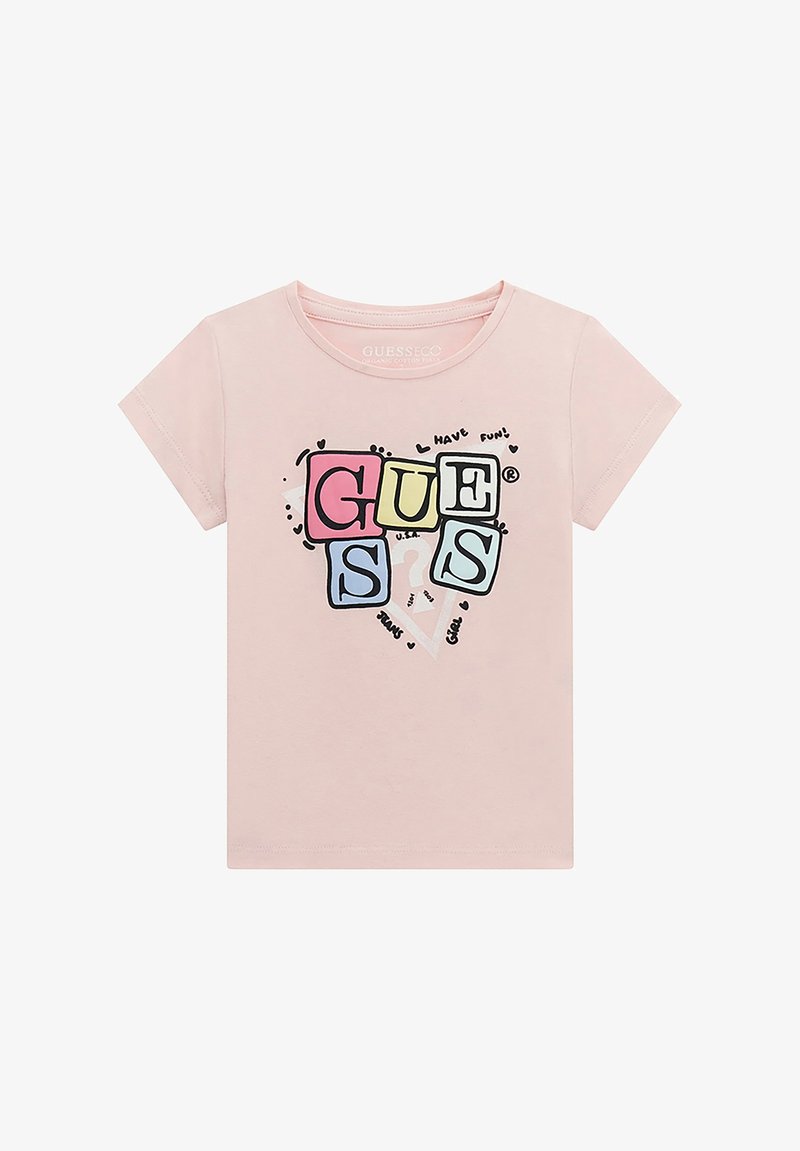 Gaiši rozā kokvilnas T-krekls ar īsām piedurknēm. Tam ir grafiskais dizains ar vārdu "GUESS" krāsainos kvadrātos un izklaidīgiem akcentiem.