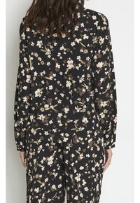 Czarny komplet bluzki i spodni w kwiaty z beżowymi i zielonymi motywami, długie rękawy z elastycznymi mankietami, lekki materiał i luźny krój.