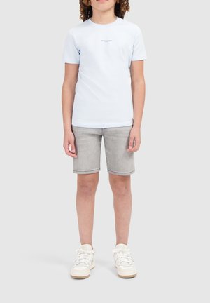Lichtblauw T-shirt met korte mouwen met "BALLIN'" in het wit gedrukt. Gecombineerd met grijze denimshorts en witte sneakers met texturen.