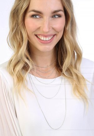 Zilveren meerlaags kettingen met verschillende kettinglengtes, tentoongesteld tegen een lichte achtergrond, gedragen met een witte blouse.