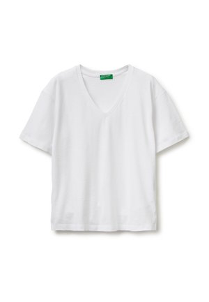 Biała koszulka z krótkim rękawem i dekoltem w kształcie litery V, rozłożona na płasko, z zieloną metką przy kołnierzu z napisem "United Colors of Benetton".