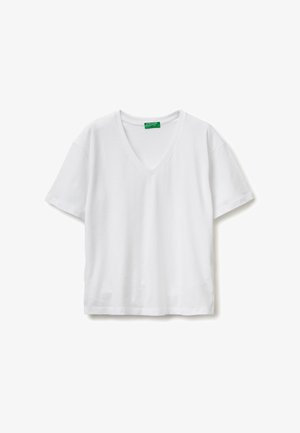 Camiseta blanca de manga corta con cuello en V, extendida sobre una superficie plana, con una etiqueta verde en el cuello que muestra la marca "United Colors of Benetton".