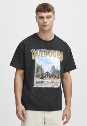 Camiseta de algodón negra con un gráfico de un paisaje montañoso que incluye árboles y una cabaña. El texto dice "El AIRE LIBRE" y "¡Sal y respira aire fresco!"