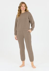 Bruine sweatshirt met een ronde hals en lange mouwen, gecombineerd met bijpassende tapered broek met elastische boorden en zijzakken.