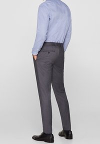 Pantaloni grigi su misura con una vestibilità slim, dotati di una tasca posteriore e una texture liscia, abbinati a una camicia a maniche lunghe di colore azzurro chiaro.