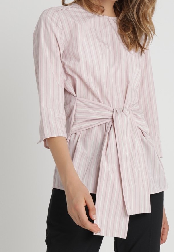 Blouse rayée rose clair à manches trois-quarts, avec un détail de taille nouée et une coupe décontractée. Fabriquée en tissu lisse et léger.