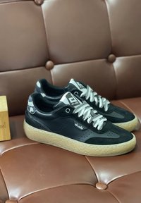 Zapatillas negras con una parte superior texturizada, materiales de ante y cuero, suela gruesa beige y cordones en contraste; logo de la marca en el lateral.