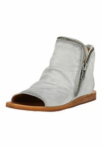 Bottine à bout ouvert en daim gris clair avec fermeture éclair latérale et semelle plate en bois, montrant une texture de matériau douce et légèrement froissée.