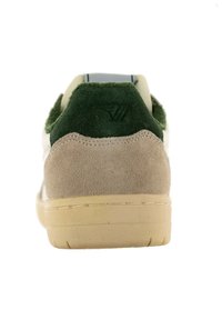 Zapatilla de ante y textil, con un talón verde, parte superior beige y suela texturizada. Logotipo grabado en el talón. Diseño clásico de corte bajo.