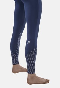 Marineblaue Leggings aus dehnbarem Material mit einem strukturierten Rautenmuster an den Unterschenkeln und einem Logo auf dem Oberschenkel.