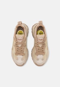 Beige sneakers med mesh- og syntetisk overdel, med tykke såler, snøredetaljer og et logo-plakett på tungen.