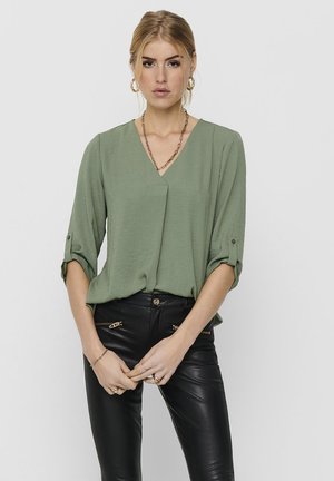 Olive green, short-sleeve blouse with a V-neckline and rolled cuffs. Made of lightweight fabric, featuring a relaxed fit and subtle draping.