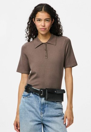 Polo marron à manches courtes avec un col, doté d'une patte de boutonnage à trois boutons. Associé à un jean bleu clair et une ceinture sac noire.