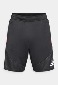 Μαύροι αθλητικοί σορτς με κόκκινα στοιχεία, ελαστική μέση, υφασμάτινες μαύρες πλαϊνές ραφές και λευκό λογότυπο στο κάτω δεξί μέρος.