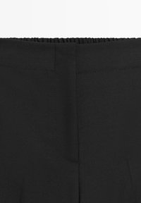 Schwarze Hosen mit elastischem Bund aus glattem Stoff; verfügen über eine hintere Naht und keine sichtbaren Taschen. Einfaches Design mit klaren Linien.