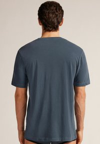 Tmavě modré bavlněné tričko s krátkým rukávem a kulatým výstřihem, s volným střihem a hladkou texturou, viditelné švy na rukávech a lemu.