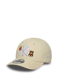 Boné bege de basebol com aba curva, apresentando o logo branco dos New York Yankees e patches bordados de um urso e batatas fritas na frente.