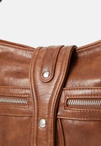 Brown leather handbag featuring a smooth texture, two zippered pockets, and a snap closure with a silver button accent.