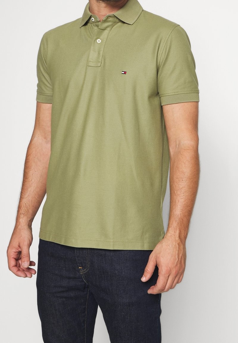 Polo vert olive en coton doux, avec un col classique, des manches courtes et un petit logo sur la poitrine gauche.