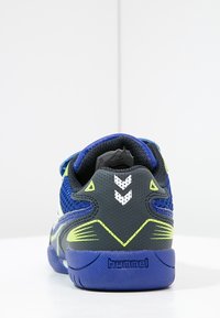 Blauwe en grijze sportieve schoen met bovenwerk van mesh, rubberen zool en neon gele accenten. Beschikt over een ventilerend ontwerp en Hummel-branding op de hiel.