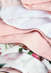 Stapel gefalteter Damenunterwäsche in Weiß, Pink und mit Blumenmustern, in Nahaufnahme gezeigt.