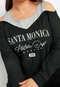 Czarna bluzka z długim rękawem i szarym dekoltem, z nadrukiem "SANTA MONICA" i "Athletic Dept." w białym kolorze, ozdobiona gwiazdkami i detalem z rokiem.