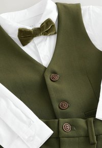 White dress shirt with olive green vest, matching bow tie, and pants with brown buttons on a flat surface.