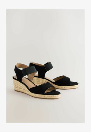 Černé semišové sandály na platformě s otevřenou špičkou, kotníkovým páskem a tkaným jutovým detailem na podpatku. Hladký povrch a minimalistický design.