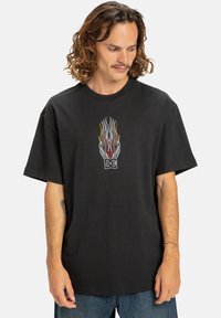 Čierne bavlnené tričko s farebnou grafikou plameňa v strede. Krátke rukávy a okrúhly výstrih s voľným strihom.