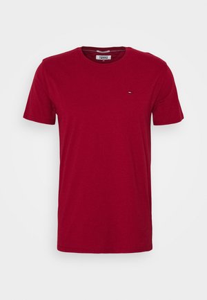 T-shirt rouge à manches courtes avec col rond, petit logo Tommy Jeans sur la poitrine et étiquette à l'intérieur du col sur fond blanc.