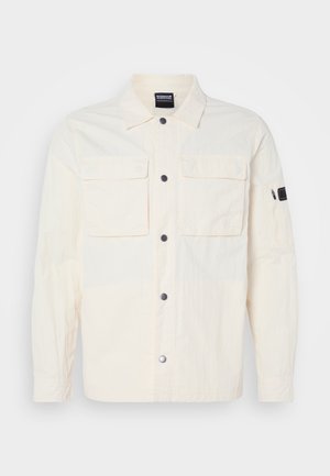 Jachetă de cămașă de culoare crem deschis, confecționată dintr-un material texturat, având închidere cu nasturi, două buzunare pe piept și un buzunar cu fermoar pe mâneca stângă.