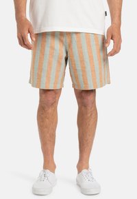 Pantaloni corti a righe in tessuto misto lino azzurro chiaro e arancione. Presentano righe verticali, una vestibilità rilassata e tasche laterali. Indossati con sneakers bianche.