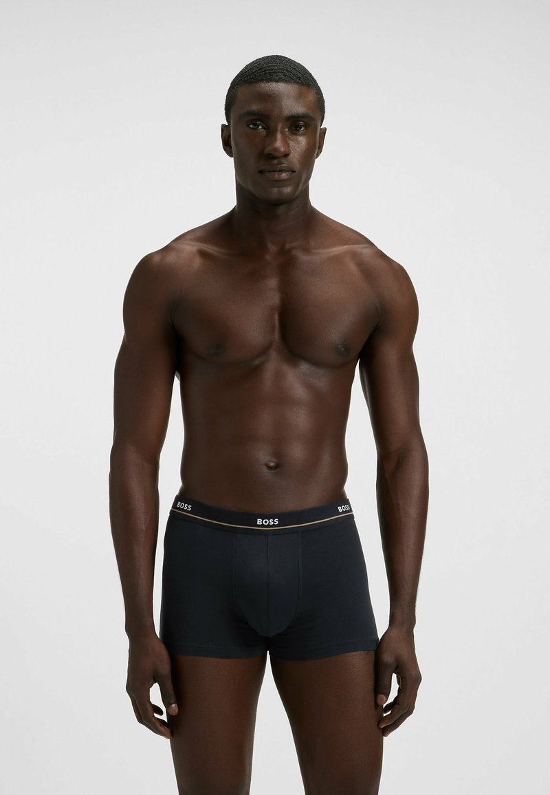 Black boxer briefs made of stretch fabric, featuring a white "BOSS" logo on the waistband, fitted design, and smooth texture.