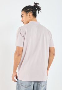 Kortermet polo skjorte i lys beige, laget av myk stoff. Har et enkelt design med en avslappet passform og en klassisk krage.