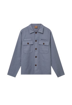 Lyseblå langærmet skjorte med knapper foran, to knaplommer foran og teksten "MM.GALLERY.20" på den øverste venstre lomme.