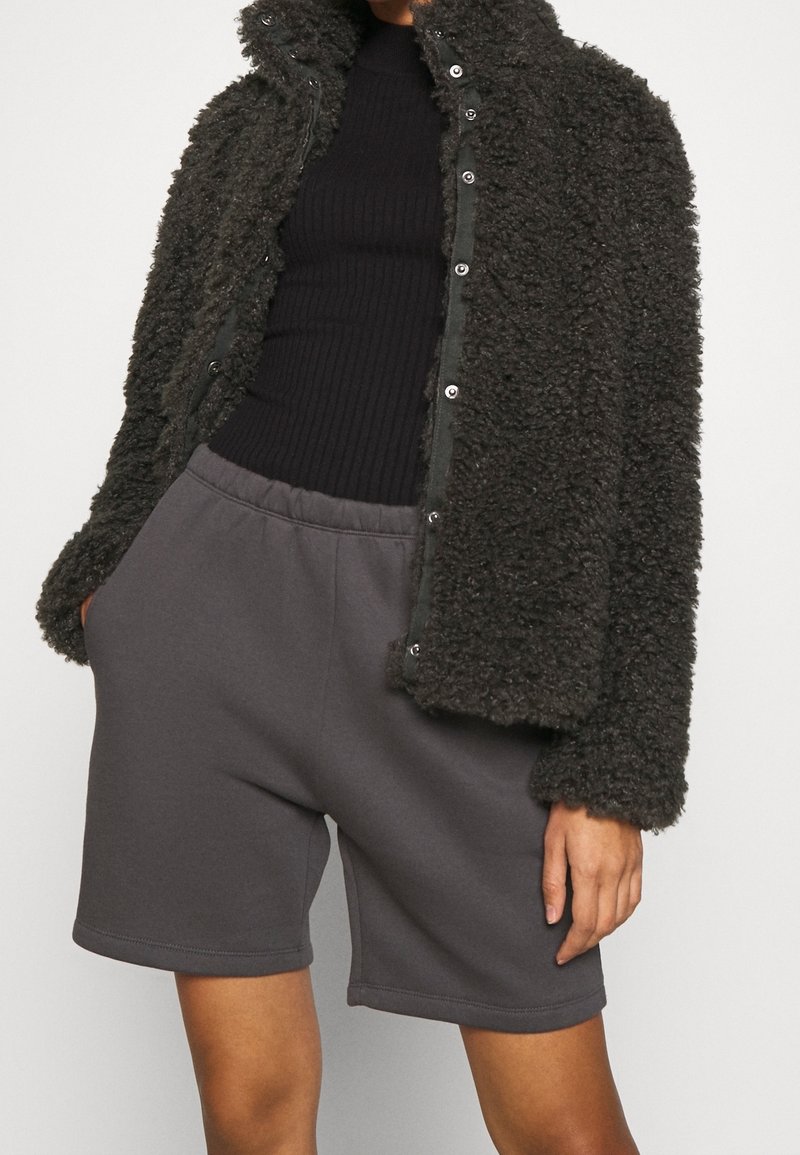 Veste en polaire grise foncée texturée avec des boutons-pression, associée à un short de survêtement gris avec une taille élastique et des poches latérales.