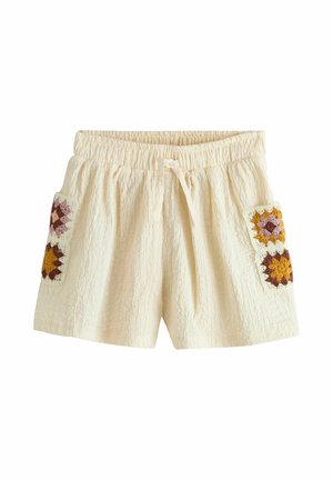 Krátke nohavice s krémovou textúrou, elastickým pásom a šnúrkou, s dvomi háčkovanými nášivkovými vreckami v horčicových, hnedých a ružových tónoch.